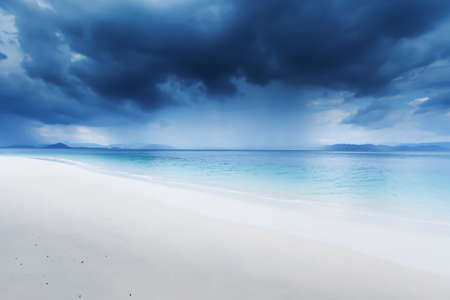 Dramatic dark storm cloud over the sea, view looking from a tranquil beach on an island....