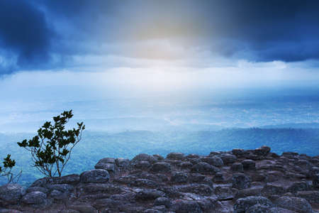 Stunning landscape of ancient sun crack on the peak of the mountain, fantastic shape of rocks and stones on the sedimentary, dark cloudy covered mountains in the backgrounds. Phu Hin Rong Kla National Park, Thailand.の写真素材