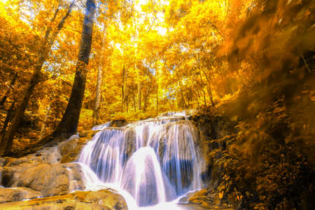 Landscape autumn waterfall in a colourful forest, bright colours leaves in seasonal. Long exposure.