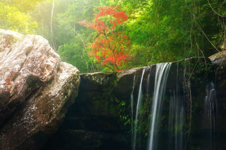 Autumn waterfall and red maple tree blurred in the background. Long exposure. Soft focus on waterfall.の写真素材