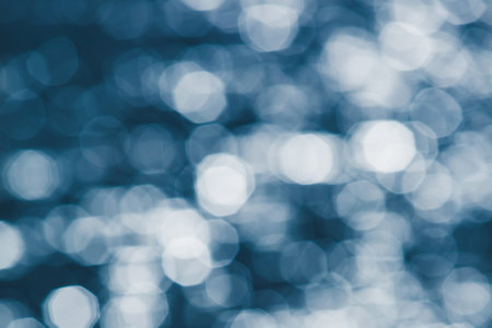 Defocus, glittering silver bokeh on surface of blue water. glowing sunrise shines on surface of water. Pure water concept.の写真素材