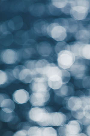 Defocus, glittering silver bokeh on surface of blue water. glowing sunrise shines on surface of water. Pure water concept.の写真素材