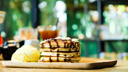 Sweet banana pancakes stack with macadamia nut and chocolate syrup topping on pancake flat lay on...