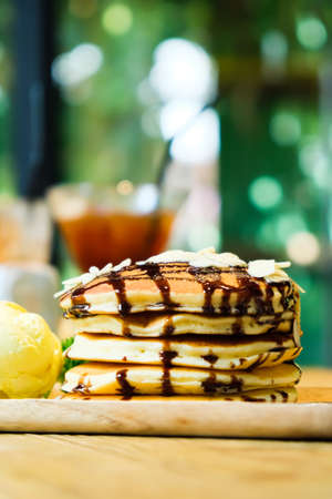 Sweet banana pancakes stack with macadamia nut and chocolate syrup topping on pancake flat lay on...
