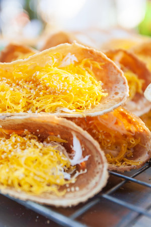 Traditional Thai dessert, Thai crispy pancake or Khanom Buang with egg threads, shrimp, sesame and coconut topping on pancakes. Street food in Thailand. Close-up.の写真素材