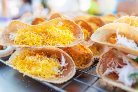 Traditional Thai dessert, Thai crispy pancake or Khanom Buang with egg threads, shrimp, sesame and coconut topping on pancakes. Street food in Thailand. Close-up.の写真素材