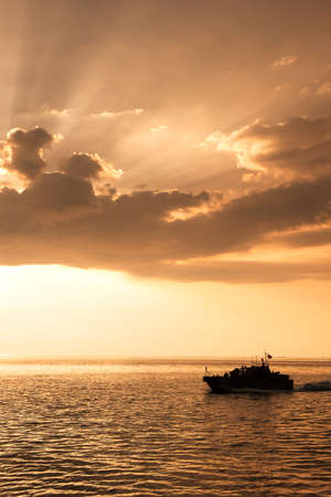 Cruiser of Royal Thai Navy sails in the sea near Thailand and Myanmar border at dusk. Dramatic...