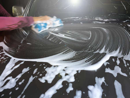 An Asian man worker washing car with sponge at a car wash. Focus on an auto.の写真素材