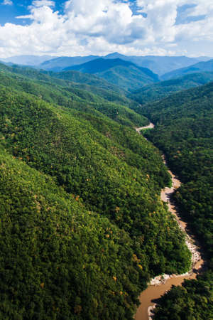 Aerial view landscape of Teak forest and a river near Thailand-Myanmar border. Green Teak forest in rain season. Pure tropical forest. Environment, climate change concepts. Focus on green plants.の写真素材