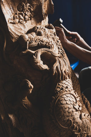 Chiang Mai, Thailand - MAY 12, 2010: Thai woodcarver carving wood dragon at his workshop studio. Traditional crave wood. Focus on wood dragon. Chiang Mai.のeditorial素材