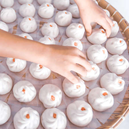 Close-up Chinese woman hands laying Baozi or Bao on bamboo basket in a typical Chinese kitchen. Chinese vegetables steamed bun. Food culture. Top view. Flat lay.の写真素材