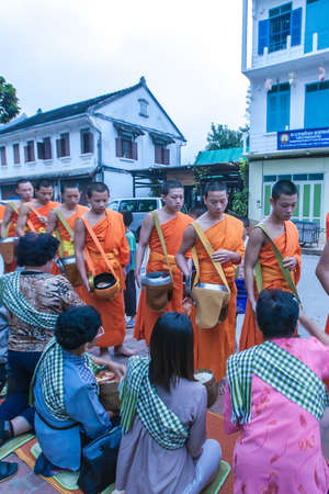 Luang Prabang, Laos - NOVEMBER 5, 2011: Buddhist monks and novices receive food during their morning alms round. Luang Prabang.のeditorial素材
