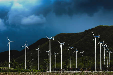 Landscape of a wind farm in a valley, storm clouds in the backgrounds. Wind turbine, windmill or wind park. Clean energy, environment concepts. Selective focus.の写真素材