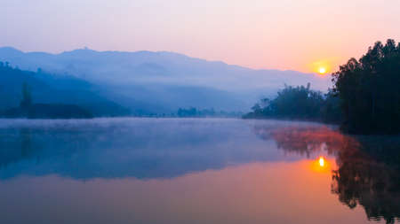 Scenery of Pa Khong Lake at sunrise, gentle morning fog covers the lake and mountains in the backgrounds, travel destinations in Dien Bien Phu, Vietnam. Soft focus on the lake.の写真素材