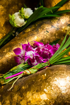 Close-up of meditation Buddha statue with orchid flowers and lotus flowers in a Buddhist temple.