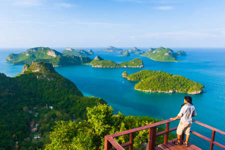 An Asian young man in casual wear stands at the terrace while relaxing islands view on sunny summer. Mu Koh Ang Thong National Park, tourist attractions in Thailand.の写真素材
