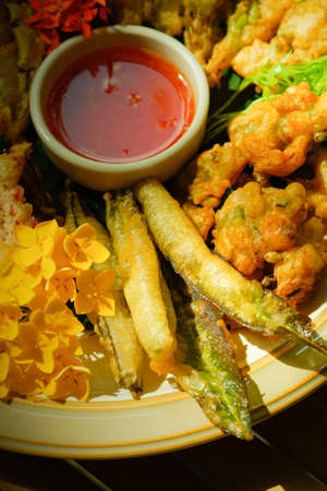 Deep-fried tropical flowers, leaves, and vegetables served on a white plate, flat lay on the bamboo table. Healthy food. Top view. Close-up. Selective focus.の写真素材