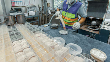 A technician wearing a face mask and glove is researching an ore in a geological laboratory, mineral processing technology. Selective focus.の写真素材