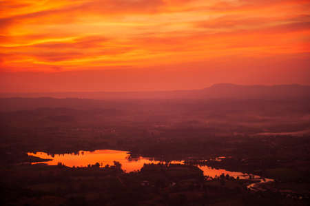 The scenery of mountains views at dusk, dramatic clouds in the colorful sunset sky reflection on a lake in the valley. Khao Kho, Thailand. Holidays, vacations concepts. Soft focus.の写真素材
