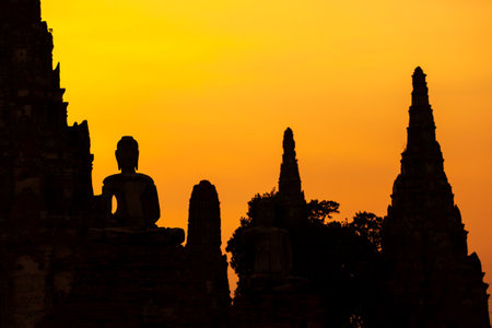 The landscape of the ancient Buddhist temple of Wat Chaiwatthanaram at dusk, the ancient Buddha statue, and the pagoda against the sunset sky. Ayutthaya Historical Park, Thailand.の写真素材