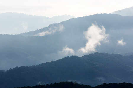 The scenery of blue mountains during sunrise, soft mist drifting over a valley. Chiang Mai, Thailand.の写真素材