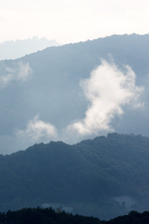 The scenery of blue mountains during sunrise, soft mist drifting over a valley. Chiang Mai, Thailand.の写真素材