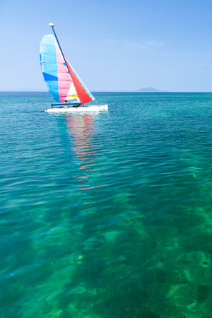 A sailboat sailing in the blue sea near a tropical island on a sunny summer. South Thailand.の写真素材