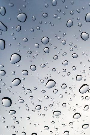 Raindrops on the glass look up to the sky blurred in the background.の写真素材