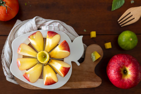 A close-up of a fresh red apple fruit on a round apple slicer on a wooden board for breakfast.の写真素材