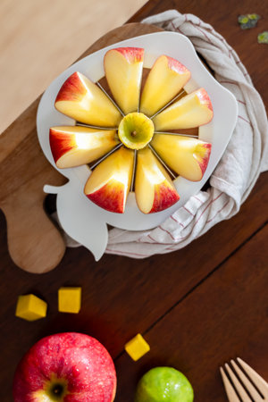 A close-up of a fresh red apple fruit on a round apple slicer on a wooden board for breakfast.の写真素材