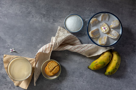 A close-up of a Banana in coconut milk served in a bowl with a glass of banana smoothie and ripe bananas, a traditional Thai dessert. Top view. Flat lay.の写真素材