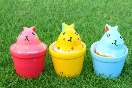 Colorful rabbits in ceramic cups on grass backgroundの写真素材