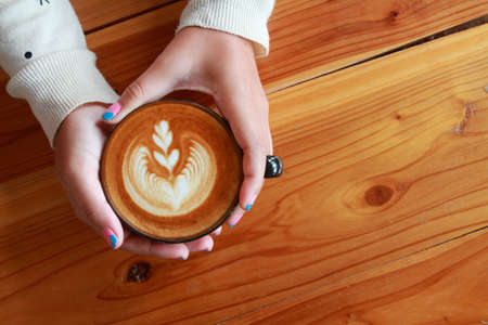 beauty  hand woman drink hot coffee  on the brown wooden  background.の写真素材