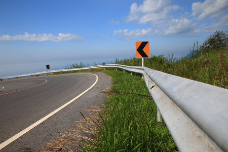 Curve road sign on down hill blue sky backgroundの写真素材