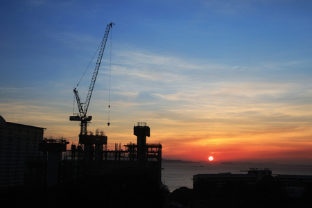 Building silhouettes and Industrial construction cranes on beautiful sunset backgroundの写真素材