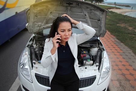 Woman business calling phone for help from the broken car. Woman business at broken car on road and...