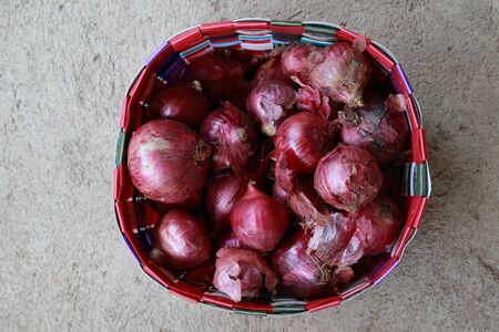 Red shallot on the basket filled with shallotsの写真素材