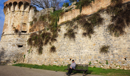 SAN GIMIGNANO, ITALY-DEC 22: Tourist take a rest under the old building in San Gimignano, Italy on December 22, 2014. San Gimignano is a small walled medieval hill town in the province of Siena, north-central Italyのeditorial素材