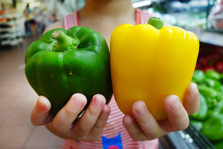 Green and red bell peppers display at a farmers marketの写真素材