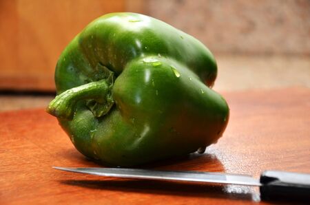 Fresh pepper vegetable on wooden cutting board with knife