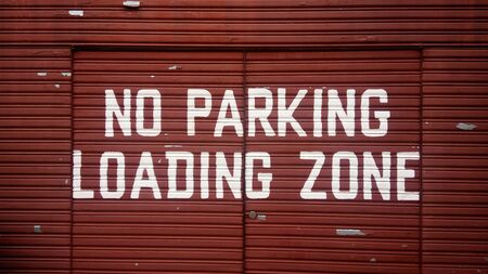No parking loading zone sign on red metal door