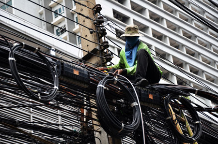 BANGKOK, THAILAND - JUNE 18, 2016: Unidentified worker works on the power line on the street Bangkok...