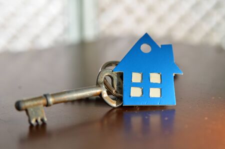 Bunch of keys with house shaped cardboard on a wooden tableの写真素材