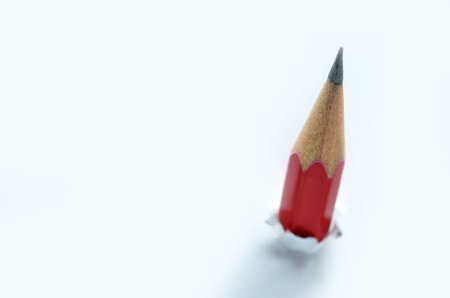 Red pencil going through a white torn paperの写真素材