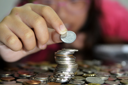 Coin piles and hand holding coin making a coin stack tower