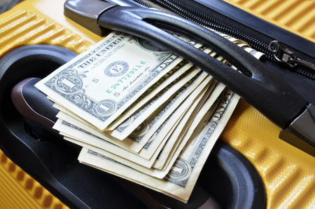Detail view of trolley suitcase with US Dollar banknotesの写真素材