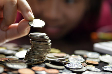 Coin piles and hand holding coin making a coin stack towerの写真素材
