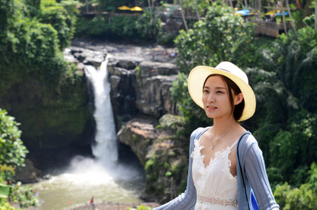 BALI, INDONESIA- 14 FEB, 2019: Young beautiful tourist visiting the Tegenungan waterfall in Bali, Indonesiaのeditorial素材