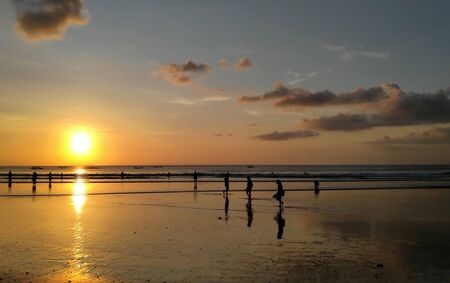 Silhouettes of people enjoying dramatic sunset at Kuta beach in Bali, Indonesiaの写真素材