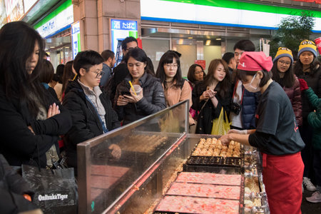 Osaka, Japan- 27 Nov, 2019: Vendor making takoyaki on a takoyaki pan in Osaka, Japan. Takoyaki is famous street food in Osaka.のeditorial素材